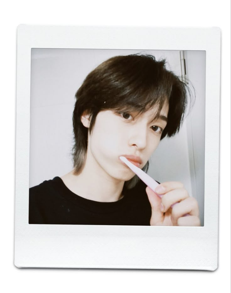 a young man brushing his teeth with an electric toothbrush in front of the mirror