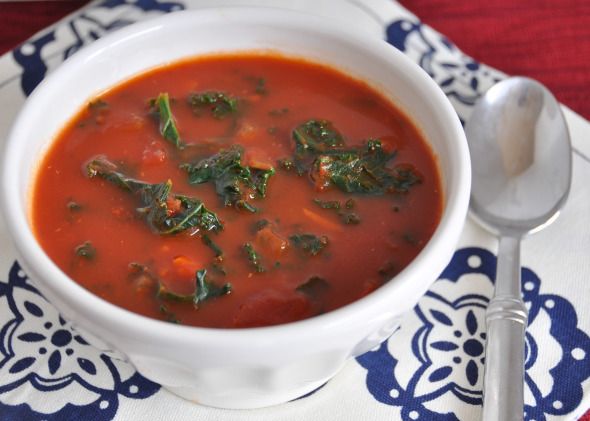 a white bowl filled with soup on top of a blue and white place mat next to a spoon