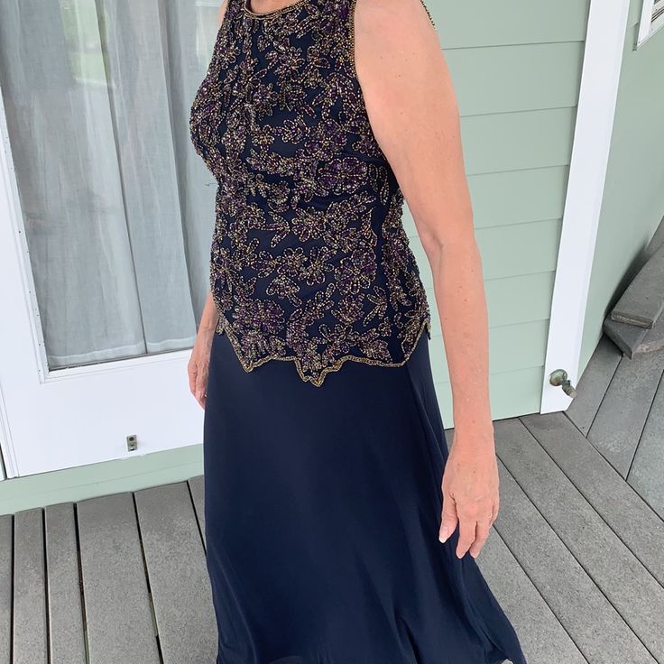 an older woman in a blue dress standing on a porch