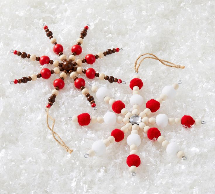 an ornament made out of beads and wooden beads on snow with red and white balls