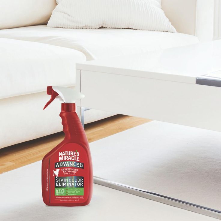 a bottle of cleaner sitting on the floor next to a white couch and coffee table