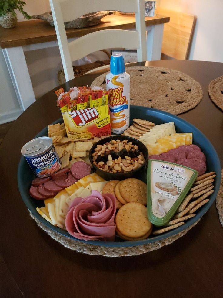 a blue bowl filled with lots of different types of cheese and crackers on top of a wooden table