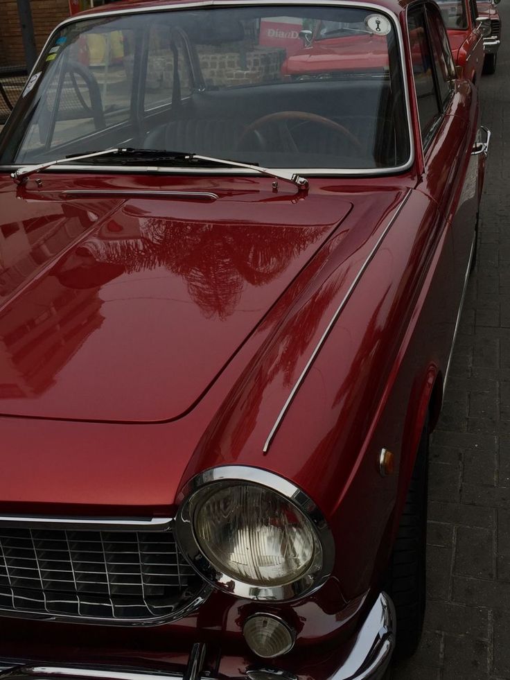 an old red car is parked on the street