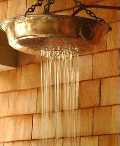 a shower head hanging from the side of a wooden building with water coming out of it