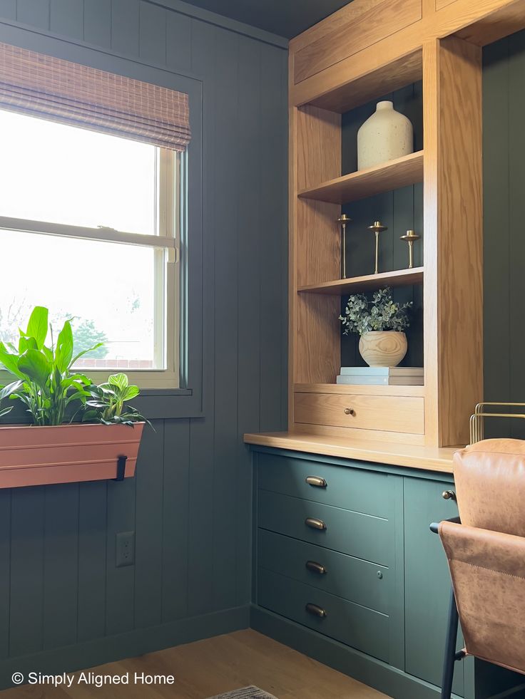 a kitchen with green painted cabinets and a potted plant in the window sill