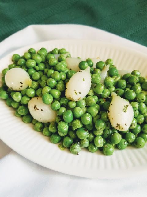 peas and potatoes on a paper plate with green cloth in the background, ready to be eaten