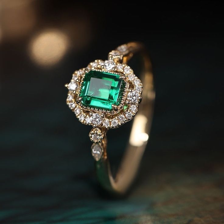 an emerald and diamond ring on a table