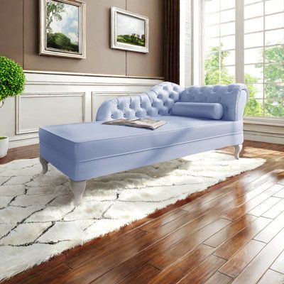 a blue chaise lounger sitting on top of a hard wood floor next to a window