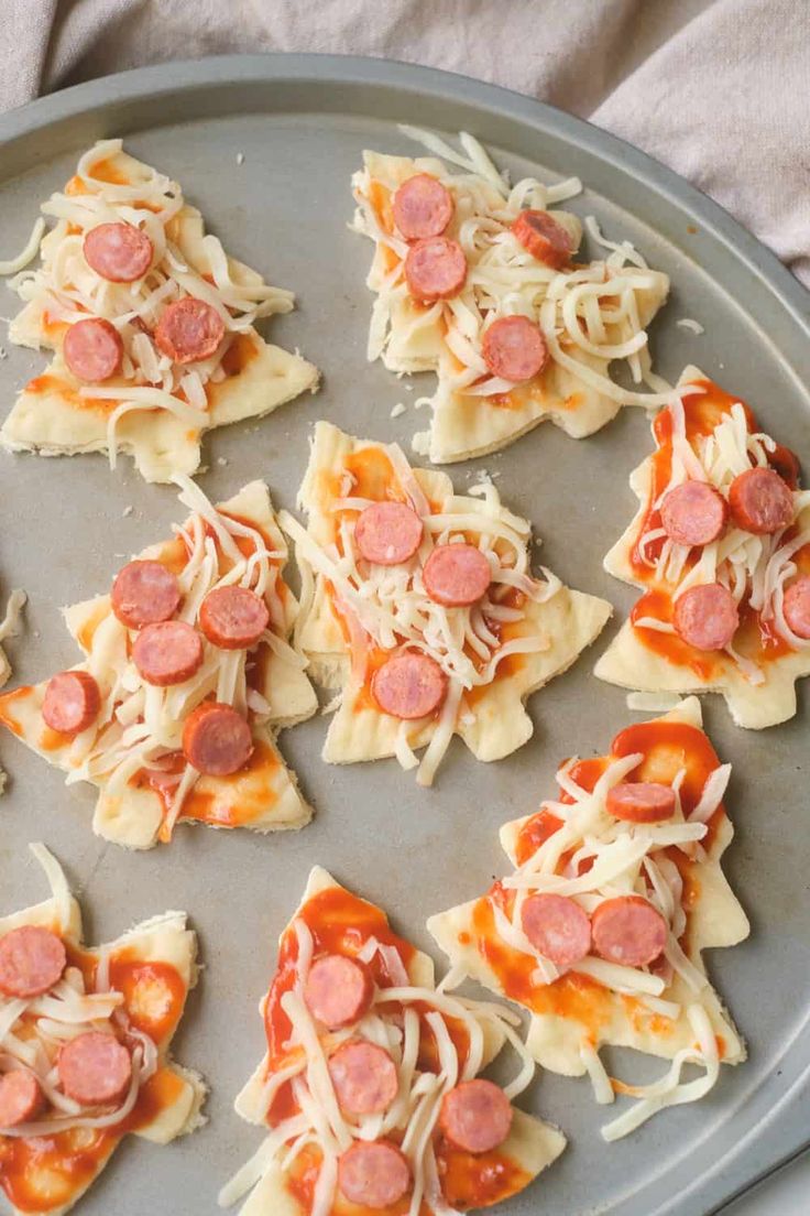 small pizzas with pepperoni and cheese are on a baking sheet, ready to be cooked