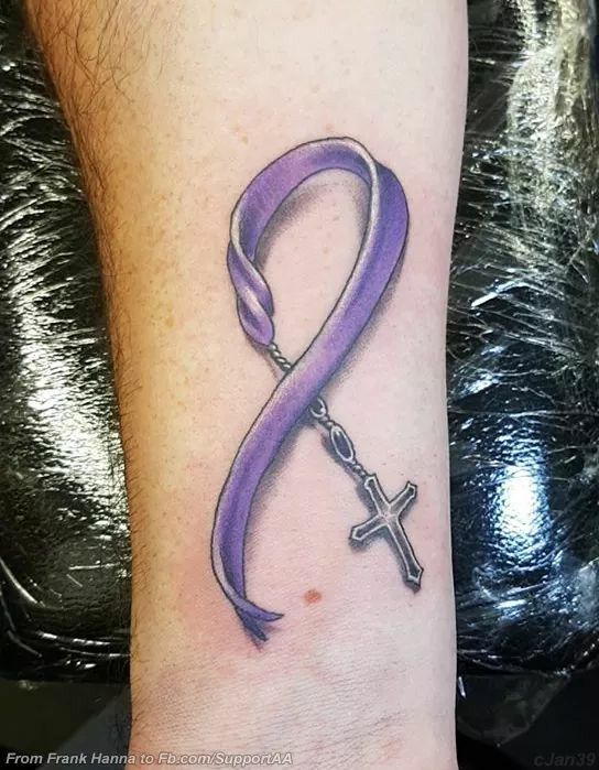 a purple ribbon with a cross tattoo on the wrist is shown in front of a person's foot