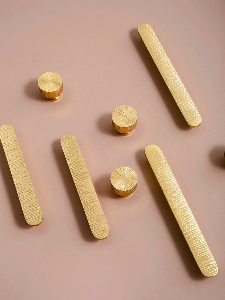 gold colored metal objects are arranged on a pink surface