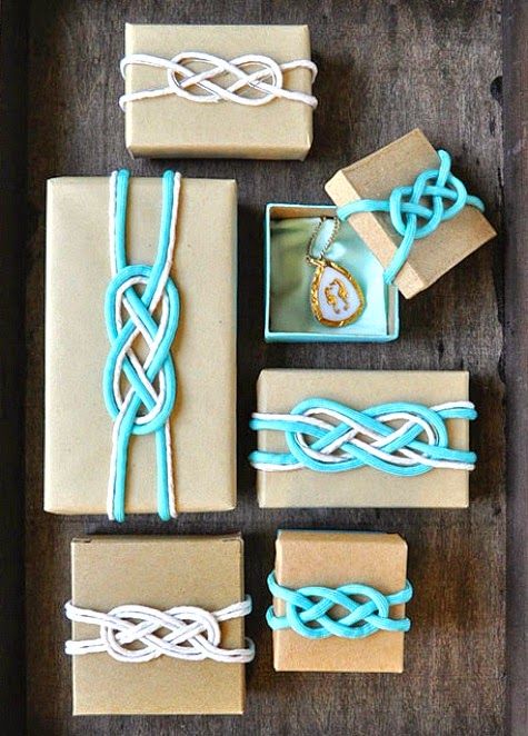 several wrapped presents with blue and white string tied around them on top of a wooden table