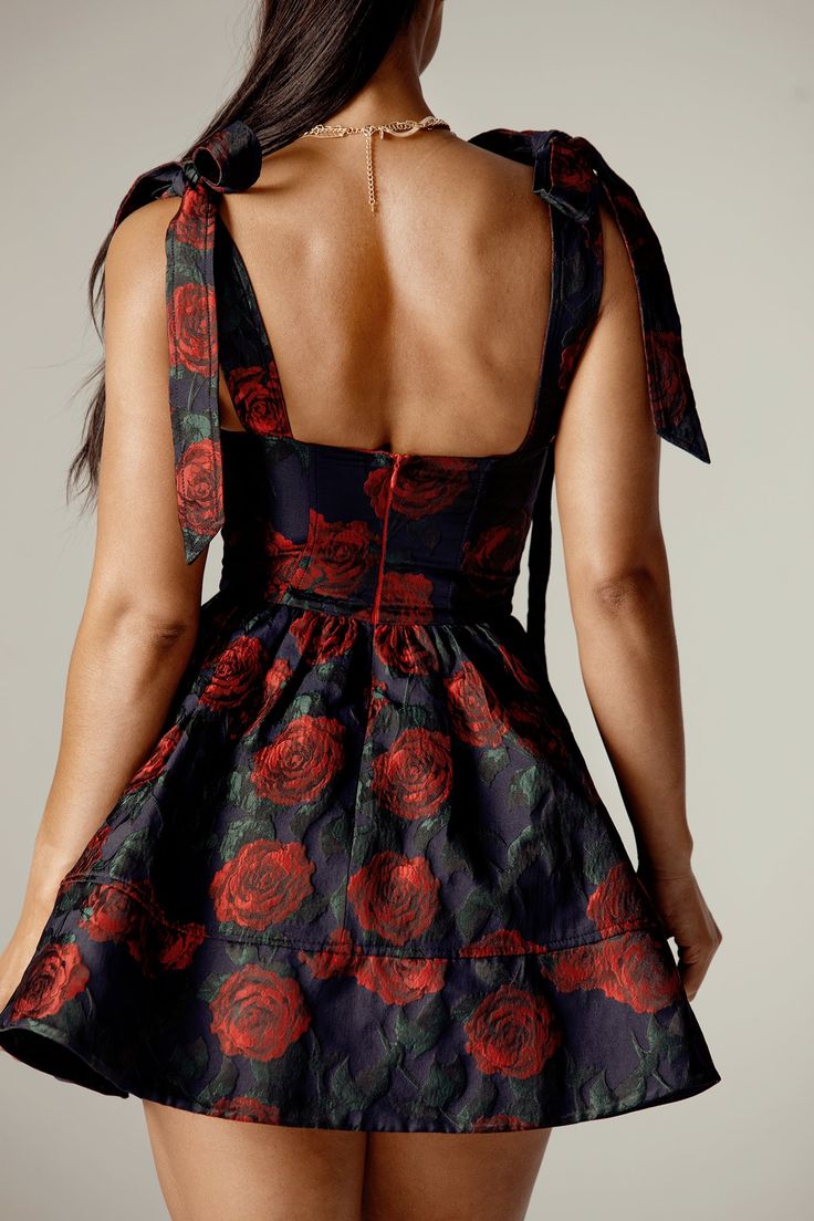 Indulge in the allure of our 'Janequa' mini dress, adorned with a captivating rose print that exudes ultra-femininity. Crafted from delicately luxurious Jacquard fabric, it epitomizes both elegance and comfort. The corseted bodice accentuates the waist, while the plunging neckline offers gentle support with a subtly seductive allure. Delicate bow tie straps add a charming touch, complementing the flouncy mini skirt for a whimsically feminine silhouette. Designed for ease, it features a convenien Fitted Mini Dress With Rose Detail For Cocktail, Fitted Rose Dress With Rose Detail, Party Dresses With Rose Print And Mini Length, Fitted Dresses With Rose Detail, Fitted Rose Mini Dress, Fitted Mini Dress With Rose Detail For Evening, Feminine Mini Dresses With Rose Detail, Chic Mini Dress With Rose Detail, Sleeveless Mini Dress With Rose Detail For Evening