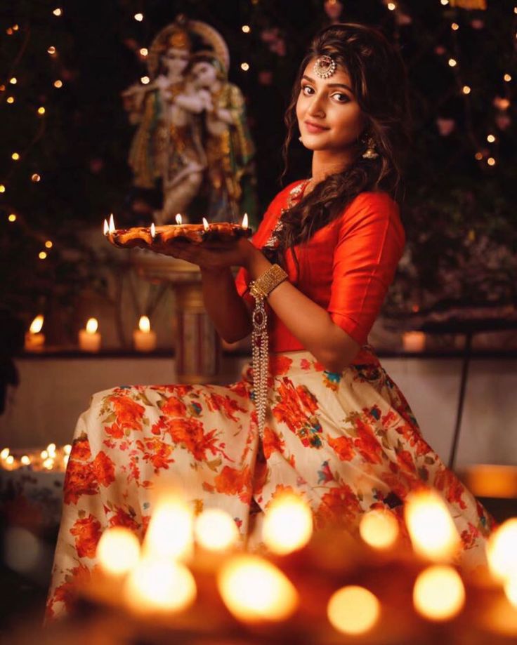 a woman sitting down holding a plate with candles in front of her and looking at the camera