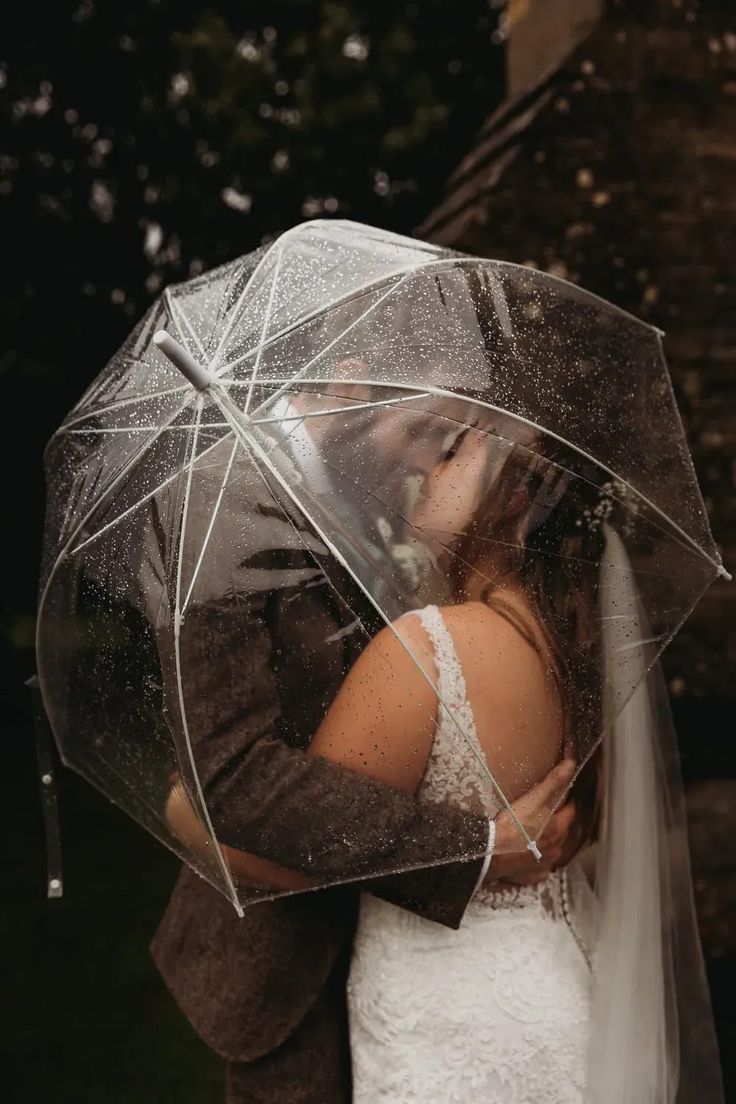 a bride and groom kissing under an umbrella