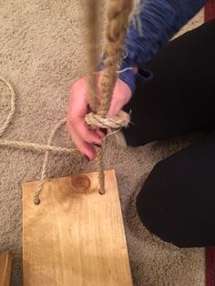 a person is tying rope to a piece of wood on the floor in front of them