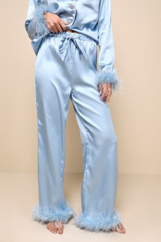 With the Lulus Dreamiest Delight Light Blue Satin Feather Two-Piece Pajama Set, you'll look so good that you'll never want to go to bed! This sleek pajama set has a sexy woven satin construction that shapes a collared neckline and long sleeves with fluffy, feather-trimmed cuffs. The relaxed, button-up bodice features dazzling, rhinestone-encrusted buttons and a front patch pocket. The matching bottoms boast a high elasticized waist with a cinching drawstring tie, that tops straight pant legs tha Blue Satin Sleep Set, Blue Satin Sleepwear Set, Blue Spring Sleep Pants, Blue Sleep Pants For Spring, Blue Satin Bottoms For Night Out, Chic Blue Sleepwear For Loungewear, Chic Blue Sets For Loungewear, Chic Blue Loungewear Sets, Elegant Light Blue Sleepwear For Loungewear