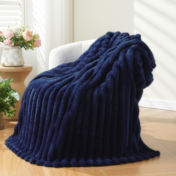 a large blue blanket sitting on top of a wooden floor next to a white chair