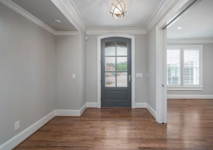 an empty living room with wood floors and white walls, along with a black door