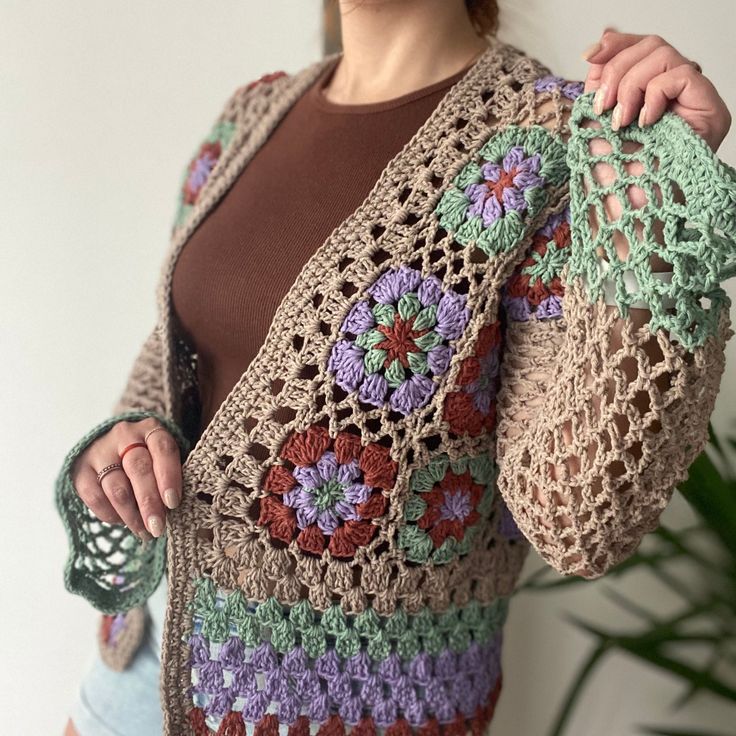 a woman is wearing a crocheted cardigan with flowers on the front and sides