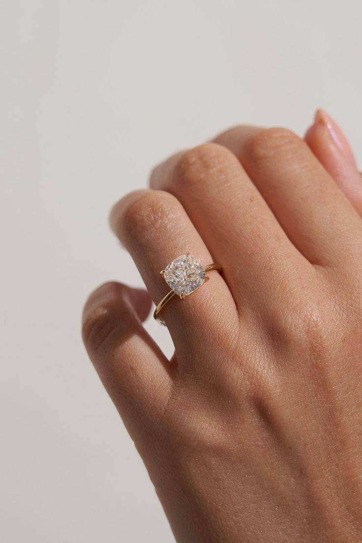 a woman's hand with a diamond ring on top of her finger, against a white background