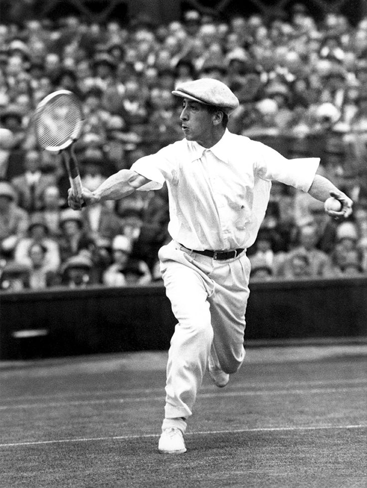 an old black and white photo of a man swinging a tennis racquet at a ball