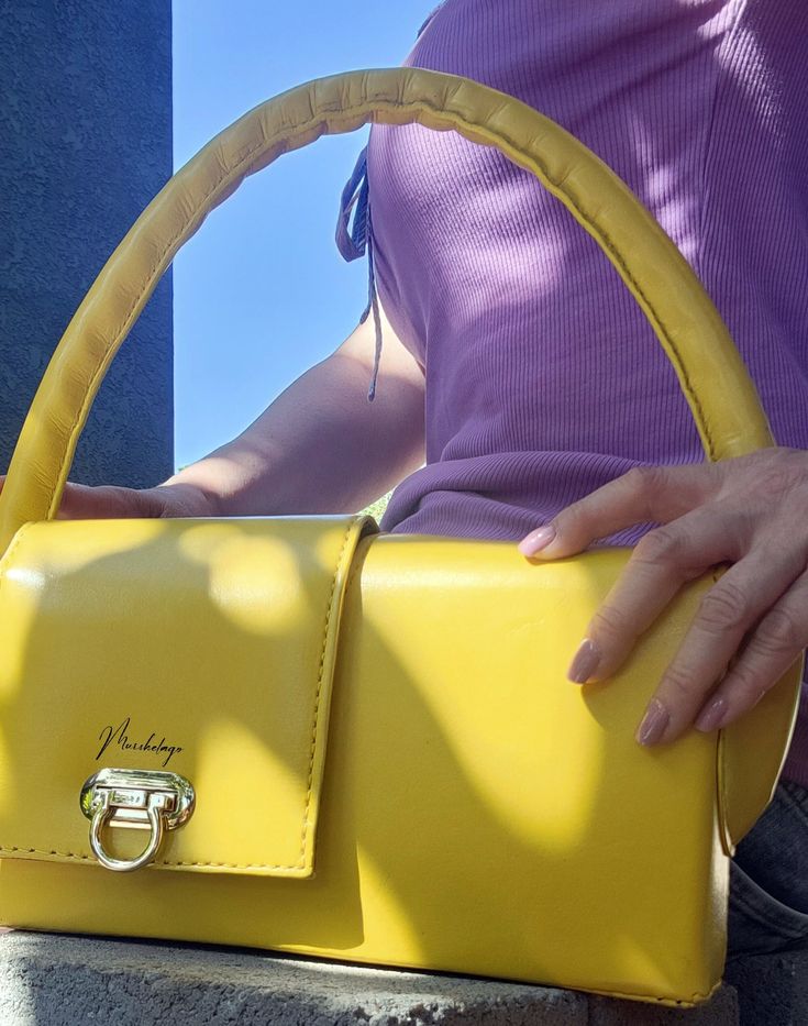 Marigold Leather Handbag, completely unique design in rectangle shape, made of American smooth veg. tanned leather. The handbag has two opposite side fold-over tops enabling you to open and close the bag from both back and forth sides. It is yellow hand dyed, finished, and polished with a top coat to make it water-resistant. The roomy interior part of the handbag has a large secure flat pocket. The handbag is carried on the shoulder and or elbow. The bottom of the bag is supported by 4 protectiv Luxury Yellow Box Bag With Detachable Strap, Modern Yellow Satchel With Top Carry Handle, Yellow Tote Box Bag With Detachable Strap, Luxury Yellow Satchel Box Bag, Chic Square Baguette Bag For Gift, Chic Square Baguette Bag As Gift, Elegant Baguette Bag With Detachable Strap As Gift, Luxury Yellow Box Bag With Top Carry Handle, Chic Yellow Box Bag For Everyday