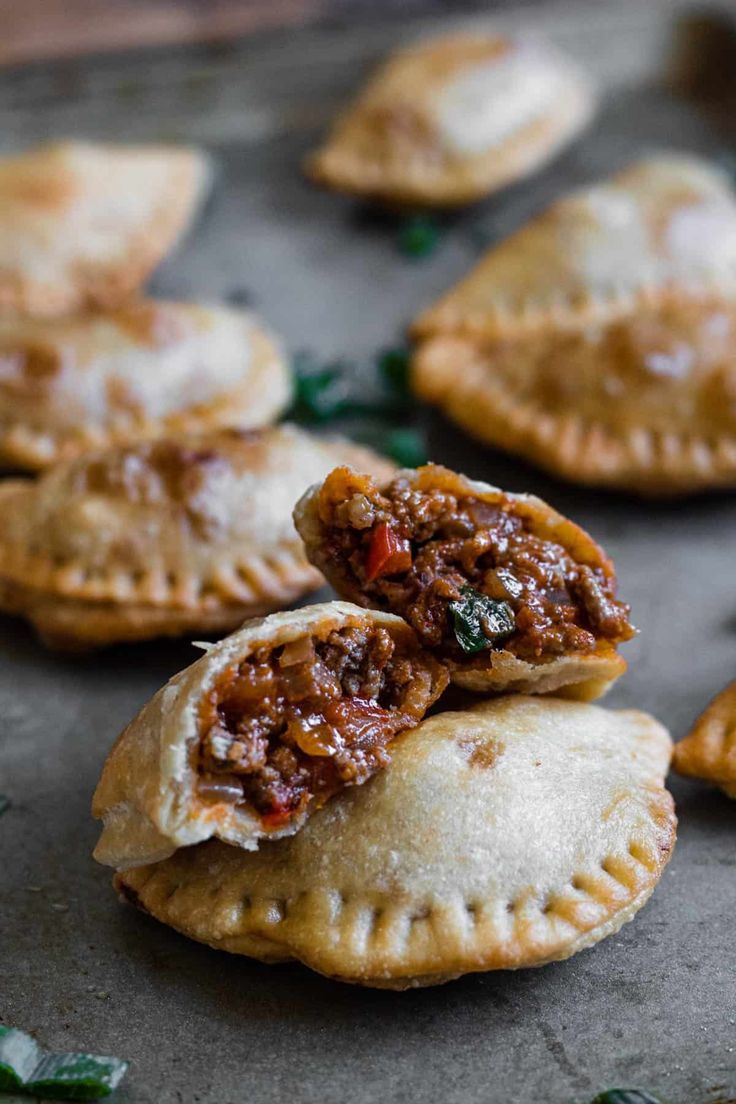 several pastries on a baking sheet with some fillings in the middle and green leaves around them