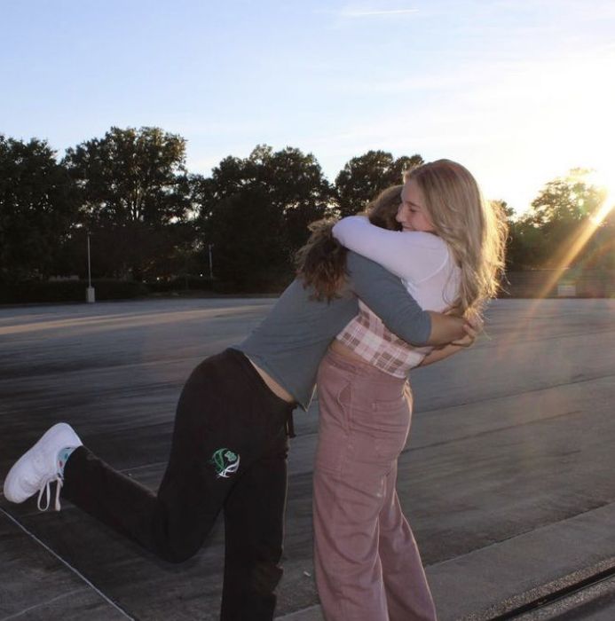 two people hugging each other on the street