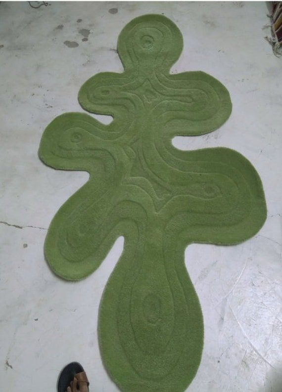 a person standing next to a green rug on the floor