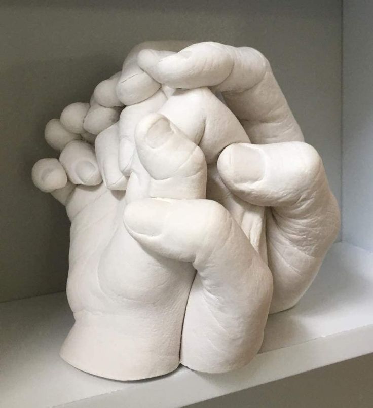 a sculpture of a hand holding something in it's palm on top of a shelf