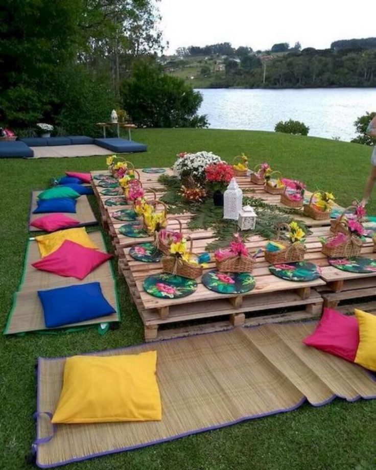 an outdoor picnic with lots of food and flowers on the table set up for people to eat