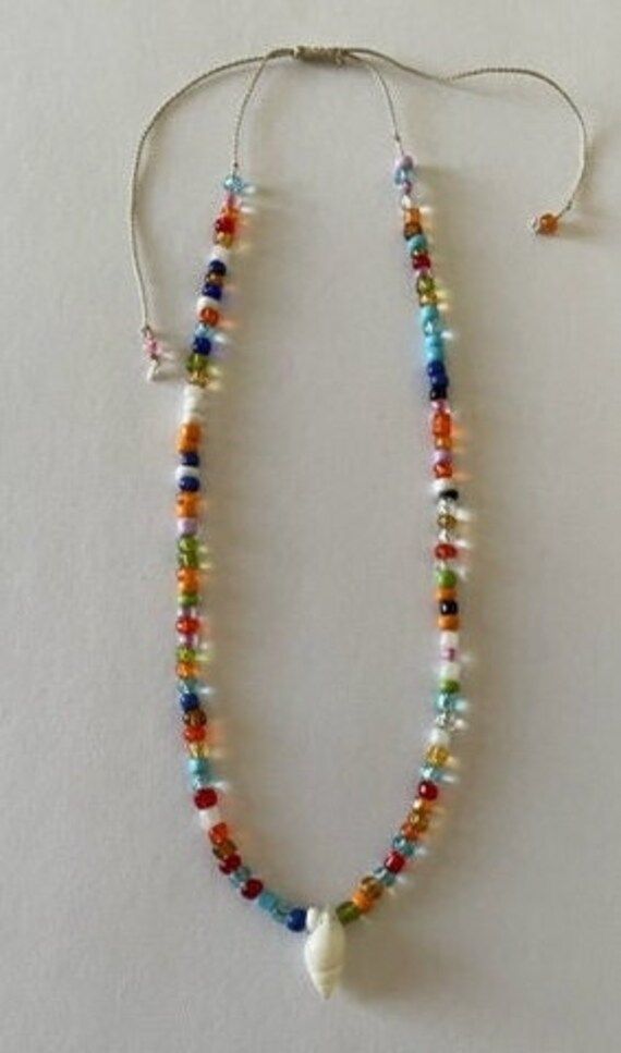 This fun necklace has little multi colour beads strung on silk. Adjustable length.In centre is a native florida shell. Brighten up any outfit Beaded Necklace White, Embellished Denim, Necklace White, Bead Stringing, Cool Necklaces, Beaded Necklaces, Miami Fl, Chain Styles, Hippie Boho