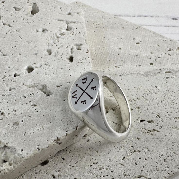 Introducing our new larger sized family initials solid silver signet ring, featuring a substantial round faced ring with wide band designed for larger finger sizes and those that like a weighty silver ring - each one is deeply custom-engraved with up to four initials (or three initials and a symbol such as a heart or star in place of the fourth) separated by crossed arrows. Dimensions and Materials: Material: Hallmarked solid sterling silver. Bezel Dimensions: 12.5mm x 12.5mm Ring Band Width: 10 Modern Sterling Silver Signet Ring With Engraving Option, Modern Silver Signet Ring With Initials, Modern Silver Signet Ring With Engraving Option, Silver Modern Signet Ring With Engraving Option, Modern Engraved Ring With Engraving Option, Modern Personalized Sterling Silver Signet Ring, Everyday Silver Signet Ring With Engraving Option, Everyday Engraved Silver Signet Ring, Everyday Silver Engraved Signet Ring