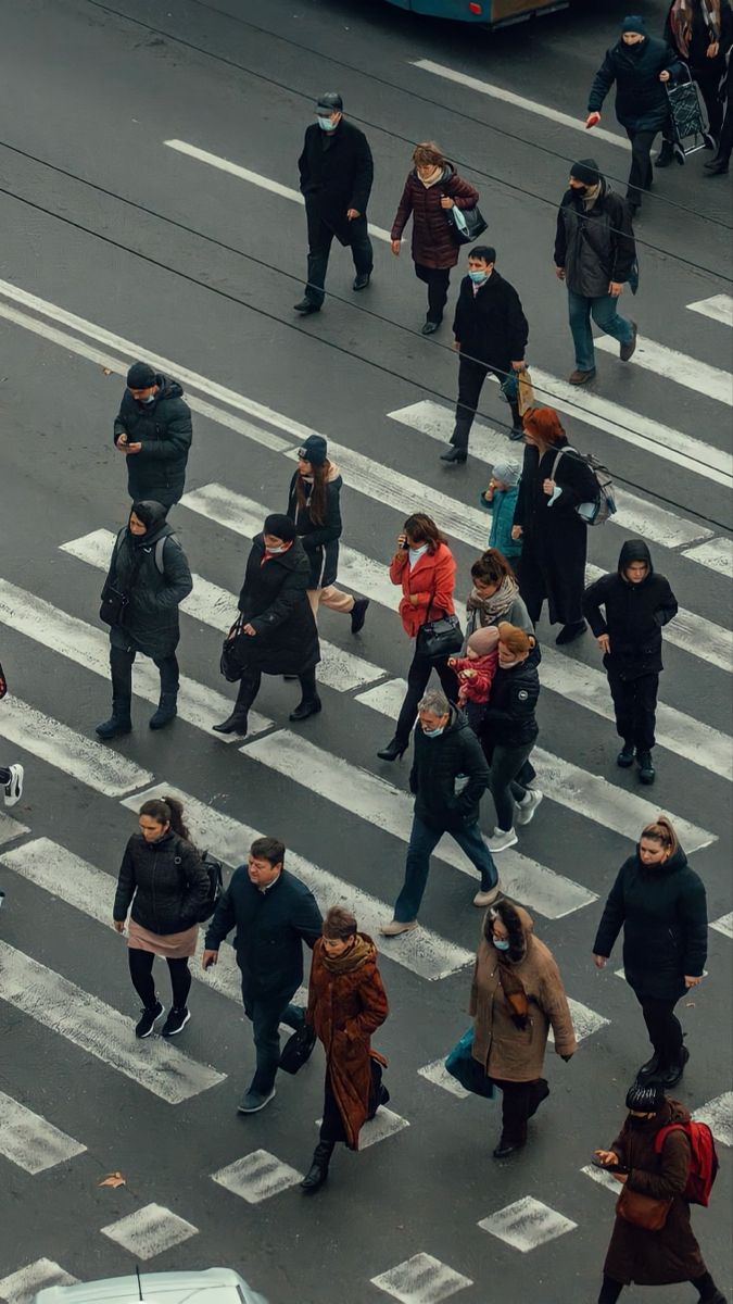 many people are walking across the street in crosswalks and onlookers