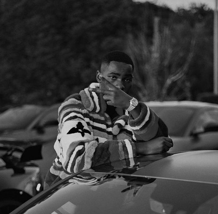 a man leaning on the hood of a car