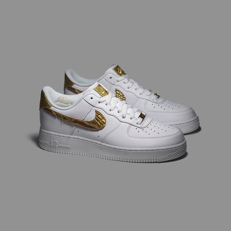 white and gold nike air force sneakers on a grey background with the soles off