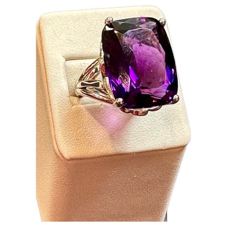 This vintage cocktail ring is a stunning piece of jewelry that features a huge 38 carat cushion-cut natural amethyst set in platinum. The amethyst measures 17 x 21 mm, giving the ring a substantial size and presence. The weight of the ring with the stone is 23.8 grams, adding to its luxurious feel and value. The beautiful work on the side of the band and on the side of the ring adds to the unique beauty of this piece. The craftsmanship is evident in every detail, making this ring a true work of Luxury Purple Amethyst Ring, Rectangular Shape, Elegant Formal Amethyst Ring With Large Stone, Luxury Purple Amethyst Rectangular Ring, Luxury Purple Rectangular Amethyst Ring, Luxury Amethyst Cushion Cut Ring For Formal Occasions, Luxury Amethyst Cushion Cut Ring For Formal Events, Luxury Cushion Cut Amethyst Ring For Anniversary, Luxury Cushion Cut Amethyst Ring For Formal Occasions, Luxury Rectangular Amethyst Ring