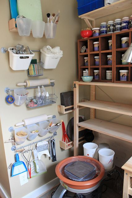 there are many craft supplies hanging on the wall in this studio area, including cups and bowls