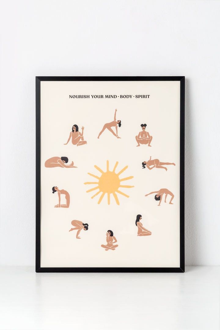 a framed poster with an image of people doing yoga in front of the sun on a white wall