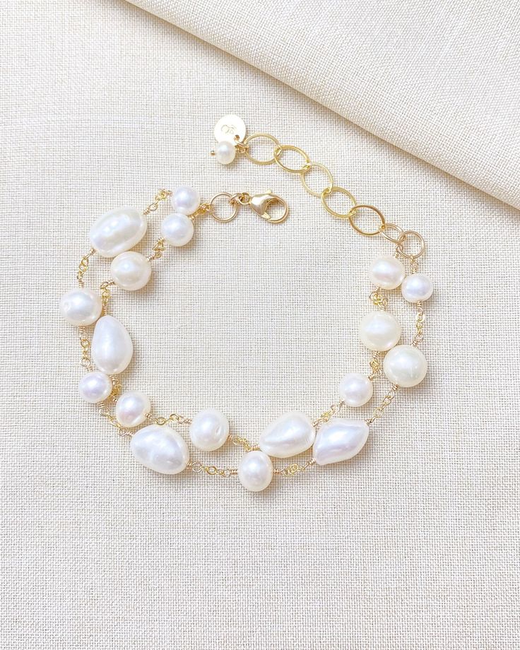 Make a classic and elegant statement with this multi-layered mixed pearl bracelet. Two handcrafted strands of differently shaped and sized pearls create a versatile accessory suitable for weddings, brunches, work, and more. The lobster clasp and extender ensure a secure and adjustable fit. Length: 7.5 inches plus 1.5-inch extender Materials: gold fill, cultured freshwater pearls GIFTING ~ Jewelry gift box included. ~ I am happy to ship directly to the recipient.  Enter their address during check Baroque Pearl Bracelets For Wedding, Baroque Pearl Wedding Bracelets, Wedding Baroque Pearl Chain Bracelet, Elegant Baroque Pearl Bracelet For Wedding, Elegant Baroque Pearl Bracelet, Multi-strand Pearl Bracelets As Gift, Elegant Baroque Pearl Beaded Bracelets For Wedding, Pearl Beaded Bracelets With Pearl Charm For Wedding, Elegant Pearl Chain Bracelet For Wedding