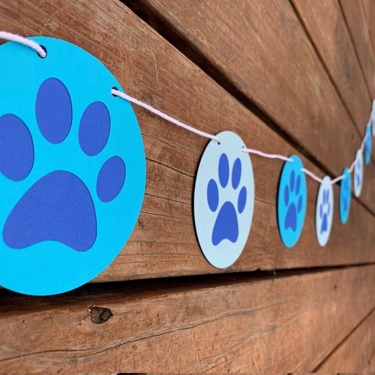 a blue and white paper banner with paw prints on it hanging from the side of a wooden fence