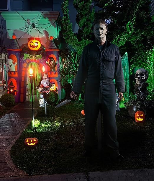 a man standing in front of a house decorated for halloween with pumpkins and jack - o'- lanterns