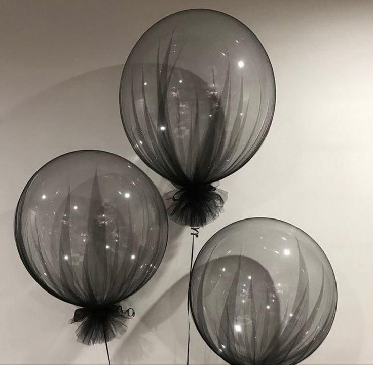 three clear balloons are hanging on the wall in front of a white wall with black accents