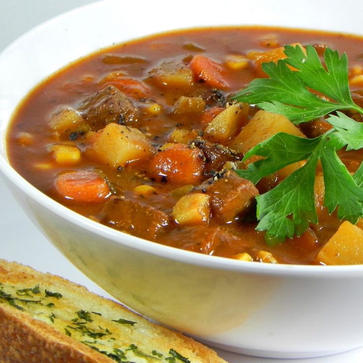 a white bowl filled with soup next to a slice of bread