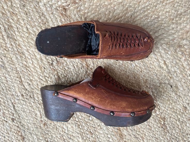 A really great pair of 1980s wood and leather clogs. They have a wooden sole with big brass studs, brown leather uppers, and a cool braided design at the toe. They are a classic slip-on style, very comfortable, and well-made. Condition: These have been well loved and worn but they do have a lot of life left in them still! Sole is in great condition aside from some small knicks and scratches. The leather is cracked and peeling but gives them a great worn in look. I would say that these are a size Vintage Brown Mules With Leather Sole, Vintage Closed Toe Mules With Leather Sole, Vintage Brown Leather Mules, Vintage Clogs With Leather Sole And Closed Toe, Vintage Mules With Leather Sole And Round Toe, Vintage Brown Mules With Leather Footbed, Vintage Leather Mules With Leather Footbed, Vintage Leather Sole Slip-on Clogs, Vintage Closed Toe Clogs With Leather Sole