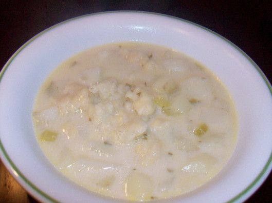 a white bowl filled with soup on top of a wooden table