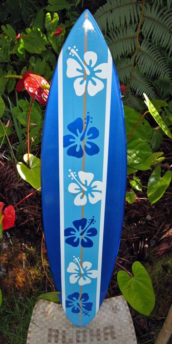 a blue surfboard sitting on top of a wooden stand in the grass next to flowers