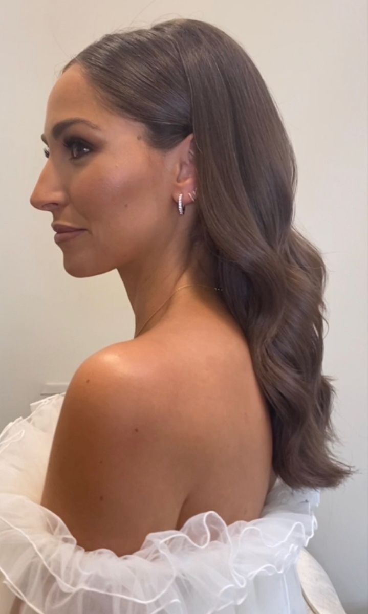 a woman in a white dress with long hair and earrings looking off to the side