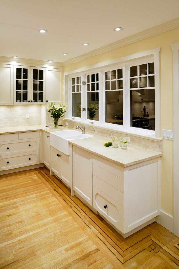 an empty kitchen with white cabinets and wood flooring on the wooden floor is shown